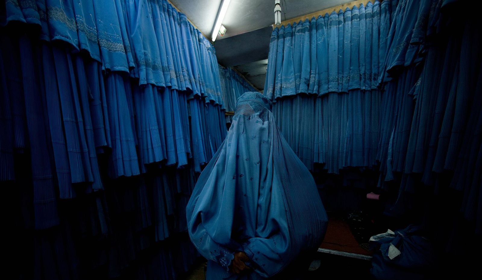 Retrato de una mujer afgana rodeada de Burkas