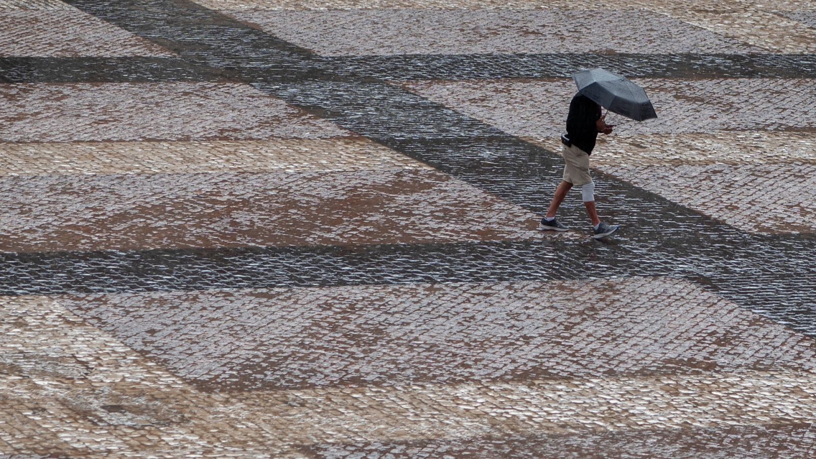 Lluvias por la DANA: una persona con un paraguas camina por la Plaza Mayor de Madrid