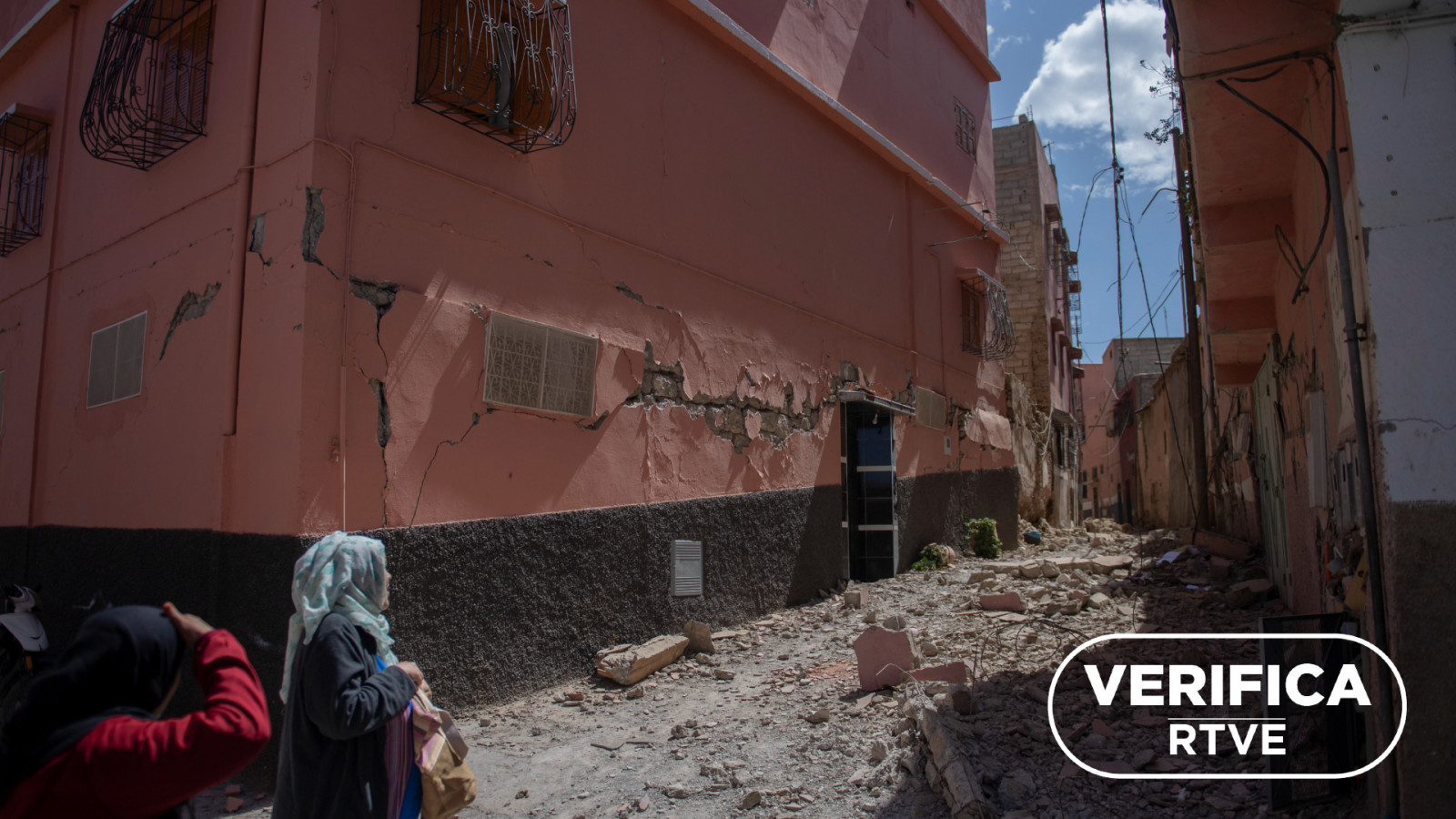 Fotografía del 10 de septiembre de 2023 que muestra mujeres caminando por una carretera dañada tras el terremoto en un barrio del sur de Marrakech, en Marruecos, con el sello VerificaRTVE en blanco