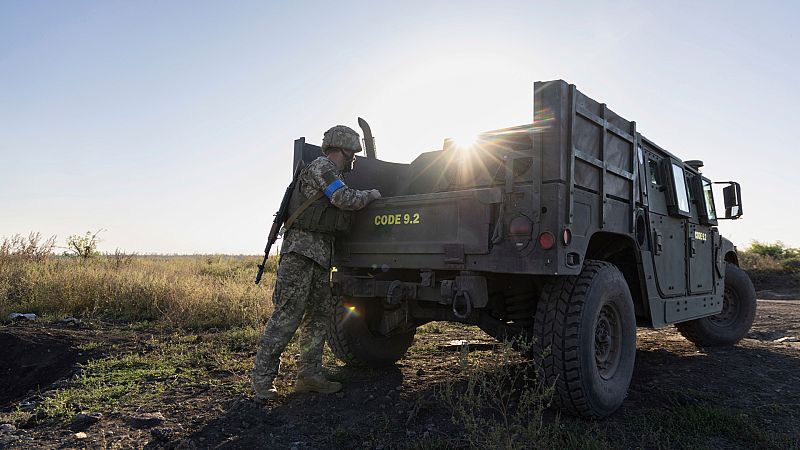 Un soldado pone equipamiento en un vehículo.