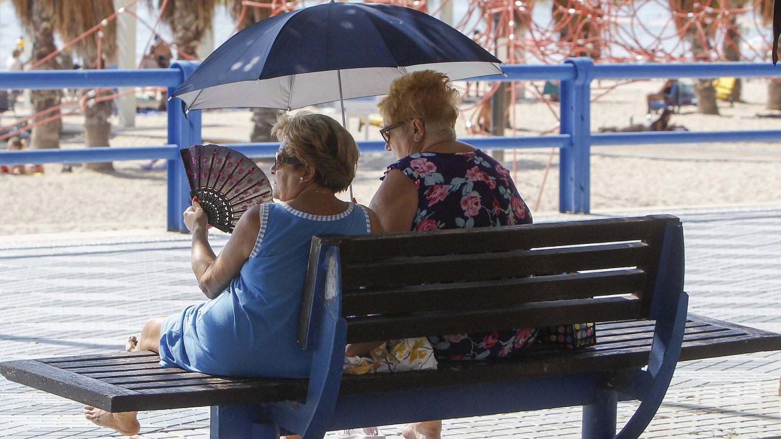 Tiempo fin de semana: Dos mujeres se protegen del sol y de calor con abanico y parasol en Alicante