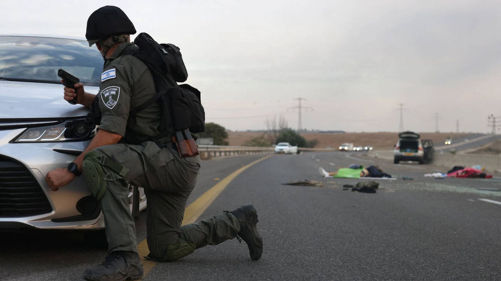 Un soldado israelí se refugia detrás de un automóvil en una carretera próxima al kibutz Gevim, cerca de la frontera con Gaza