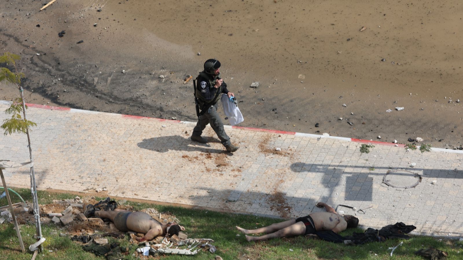 Un soldado pasa frente a los cuerpos de militantes palestinos en Sderot