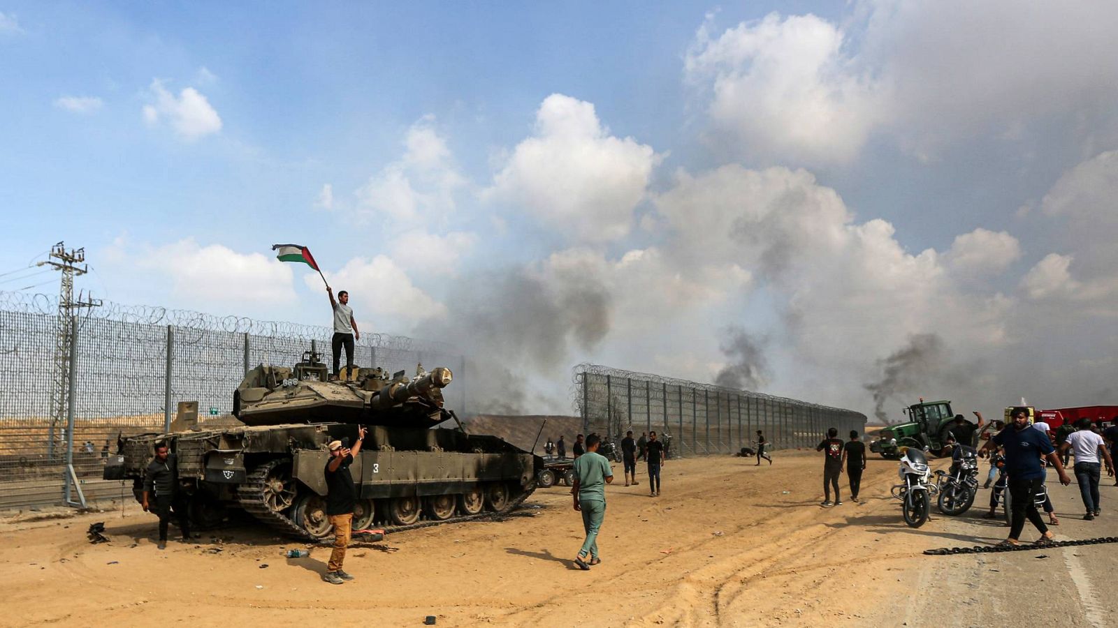 Palestinos junto a la verja que divide Gaza de Israel, tras ser asaltada al este de Jan Yunis, el pasado sábado, 7 de octubre. Foto: AP Photo/Yousef Masoud