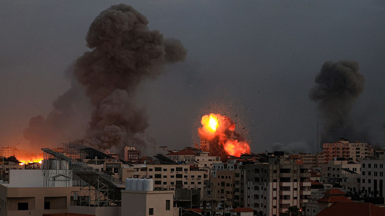 El humo se eleva y los escombros vuelan por los aires mientras cae la noche en la ciudad de Gaza durante los ataques aéreos israelíes del 9 de octubre de 2023