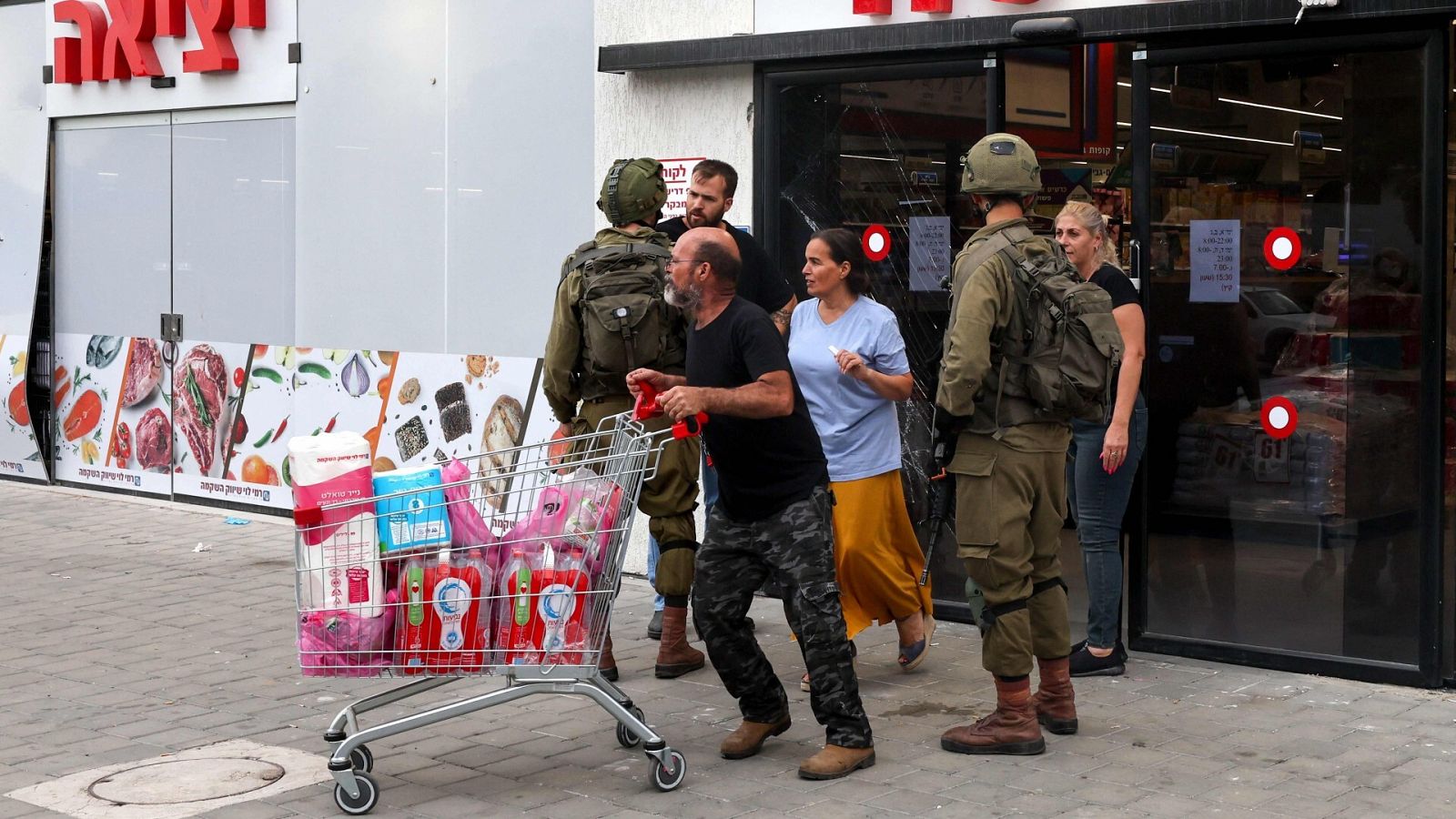 Soldados israelíes hablan con la gente que sale de un supermercado en la ciudad israelí de Sderot
