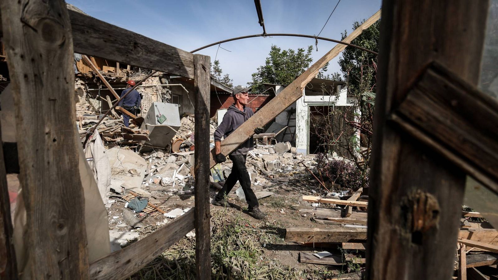 Un hombre limpia los escombros de una casa destruida tras un bombardeo en el pueblo de Bilenke