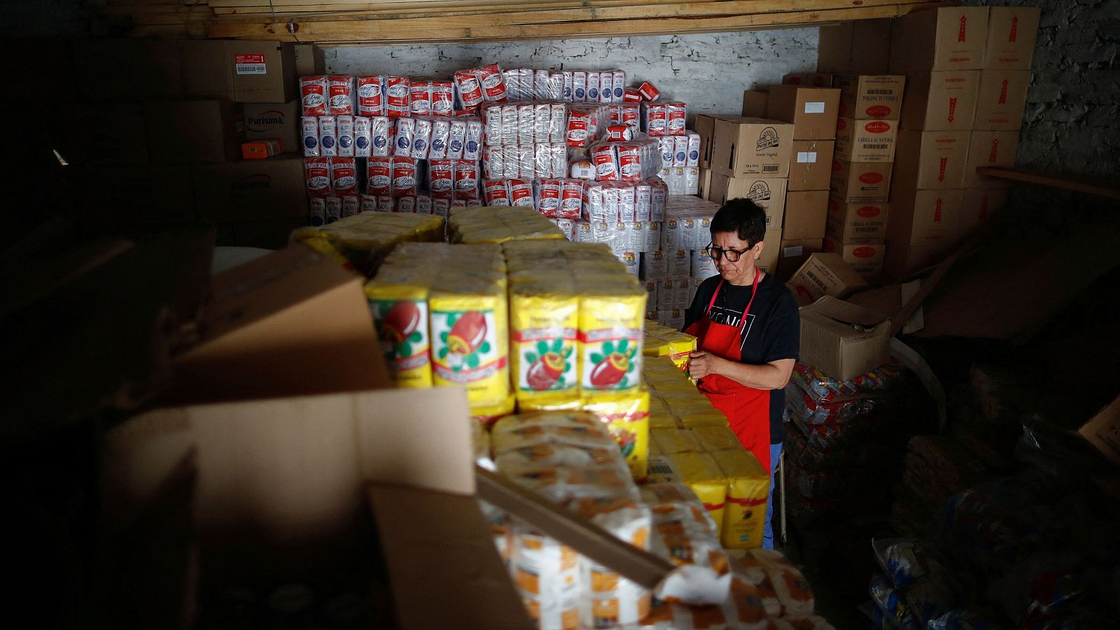 María Angélica Valenzuela, voluntaria de un centro que recibe donaciones de alimentos del Gobierno para su uso en comedores sociales, clasifica paquetes en el almacén, en el barrio obrero de Villa Fiorito