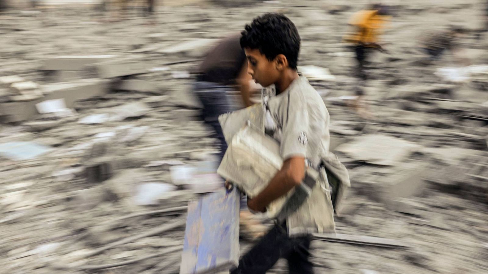 Un niño se aleja con sus pertenencias rescatadas de los escombros de un edificio atacado durante un ataque israelí en Rafah, en el sur de la Franja de Gaza, el 15 de octubre de 2023.