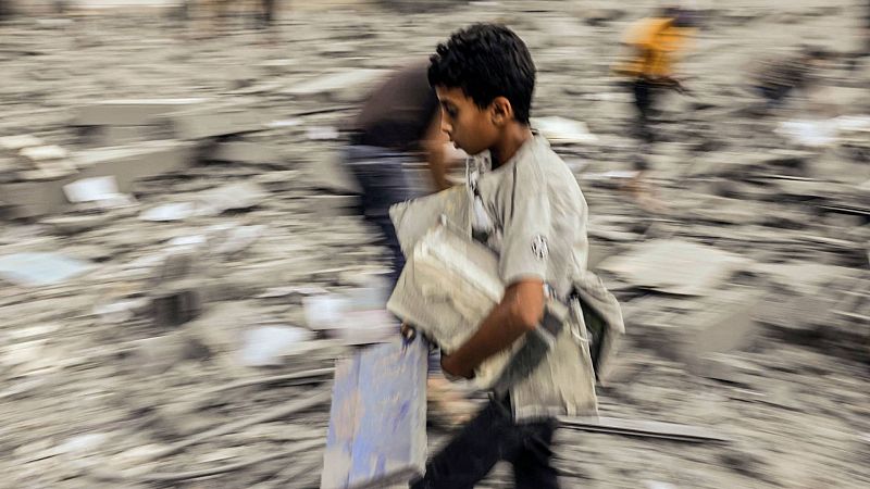 Un niño se aleja con sus pertenencias rescatadas de los escombros de un edificio atacado durante un ataque israelí en Rafah, en el sur de la Franja de Gaza, el 15 de octubre de 2023.