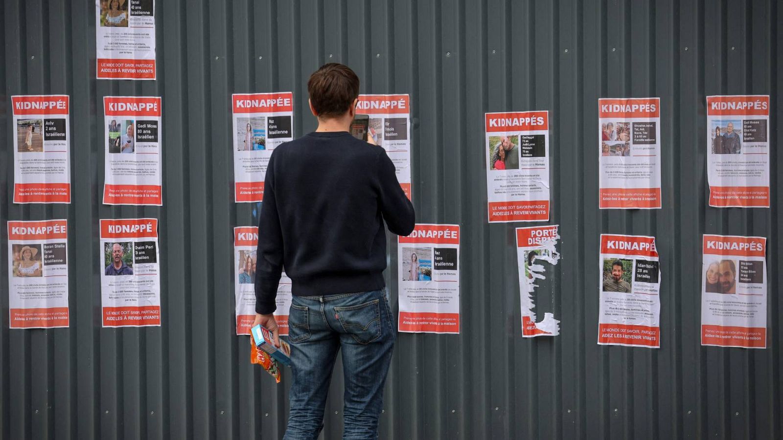 Un hombre fotografía en el centro de París, el 17 de octubre de 2023, carteles de secuestros y desapariciones que muestran a israelíes recientemente secuestrados o desaparecidos tras los ataques de Hamás contra Israel