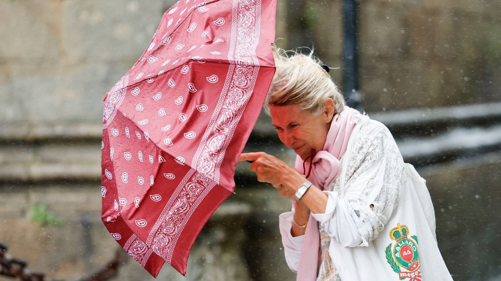 Una mujer se protege del viento y la lluvia en Santiago de Compostela, Galicia