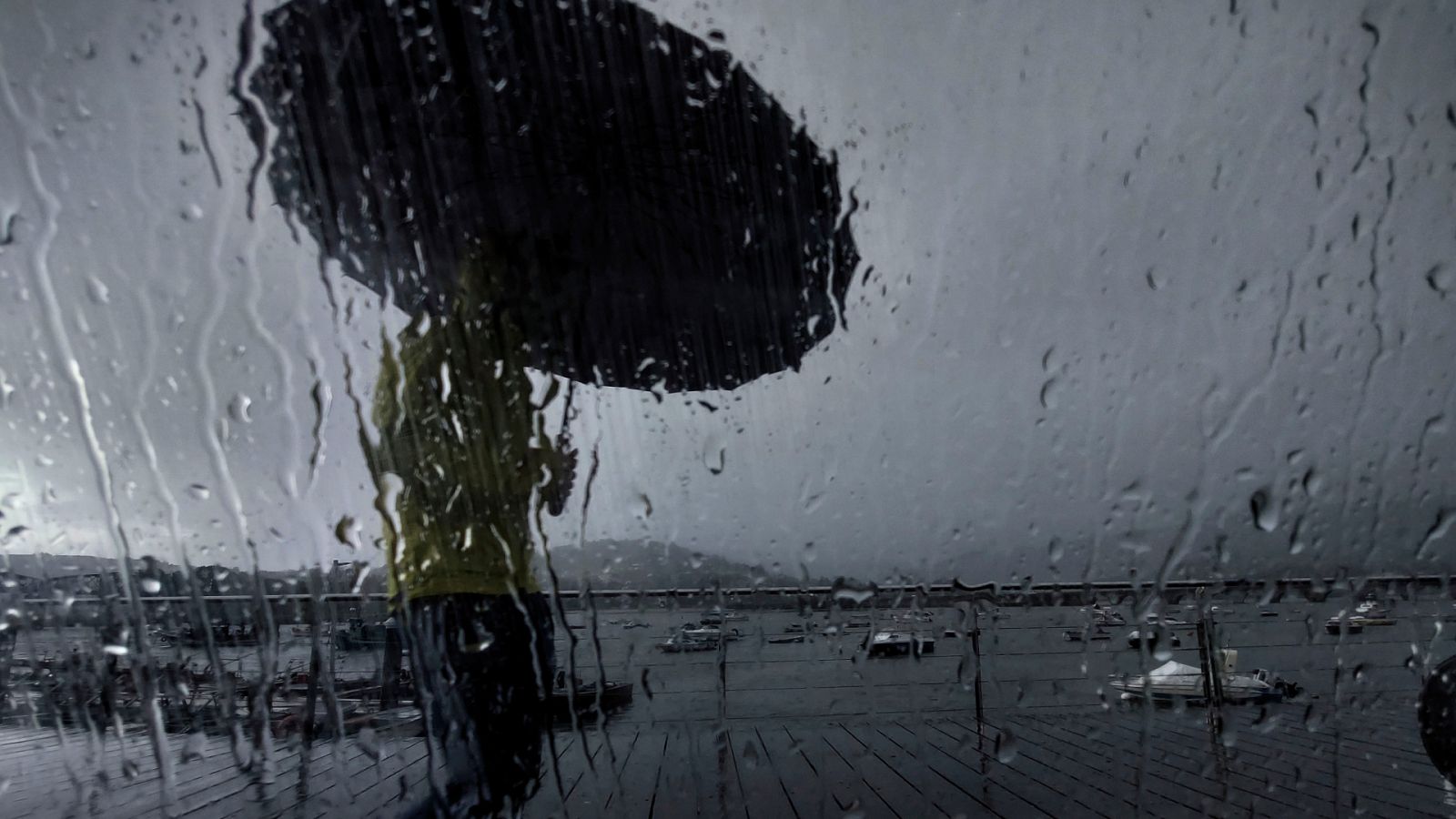 Un hombre con paraguas camina por el puerto de Pontedeume, en A Coruña.
