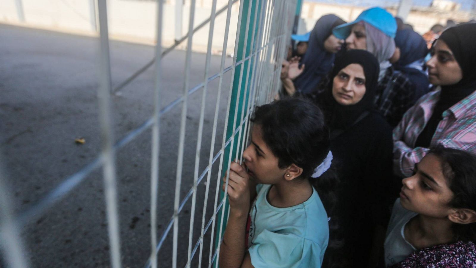 Varias personas esperan frente al paso fronterizo entre la Franja de Gaza y Egipto en Ráfah, entre ellas, niños