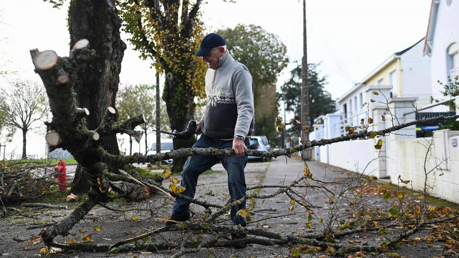 Un jubilado corta un árbol caído frente a su casa en Saint-Nazaire, oeste de Francia