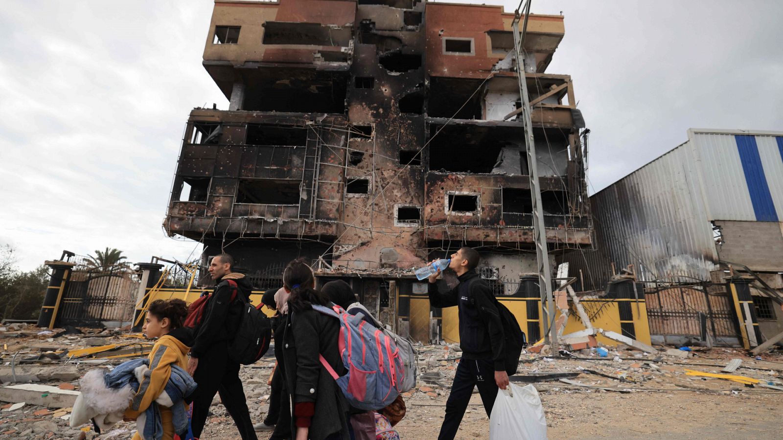 Un grupo de personas mira un edificio dañado en Gaza por la guerra con Israel.