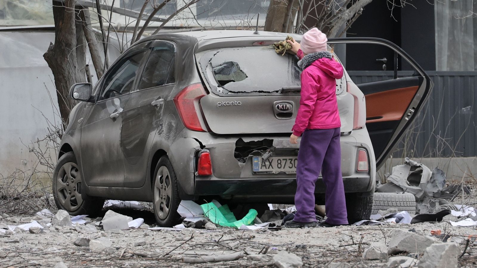 Una niña revisa el coche dañado de su familia tras un bombardeo en Járkov