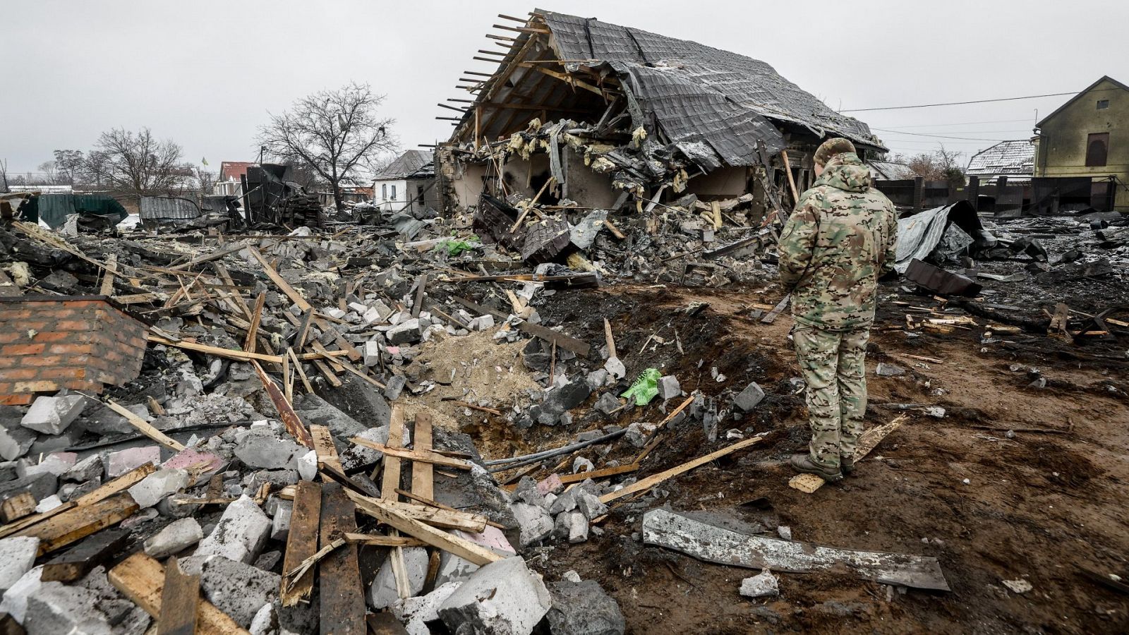 Guerra Ucrania y Rusia en directo: Un militar observa los restos de una casa destruida