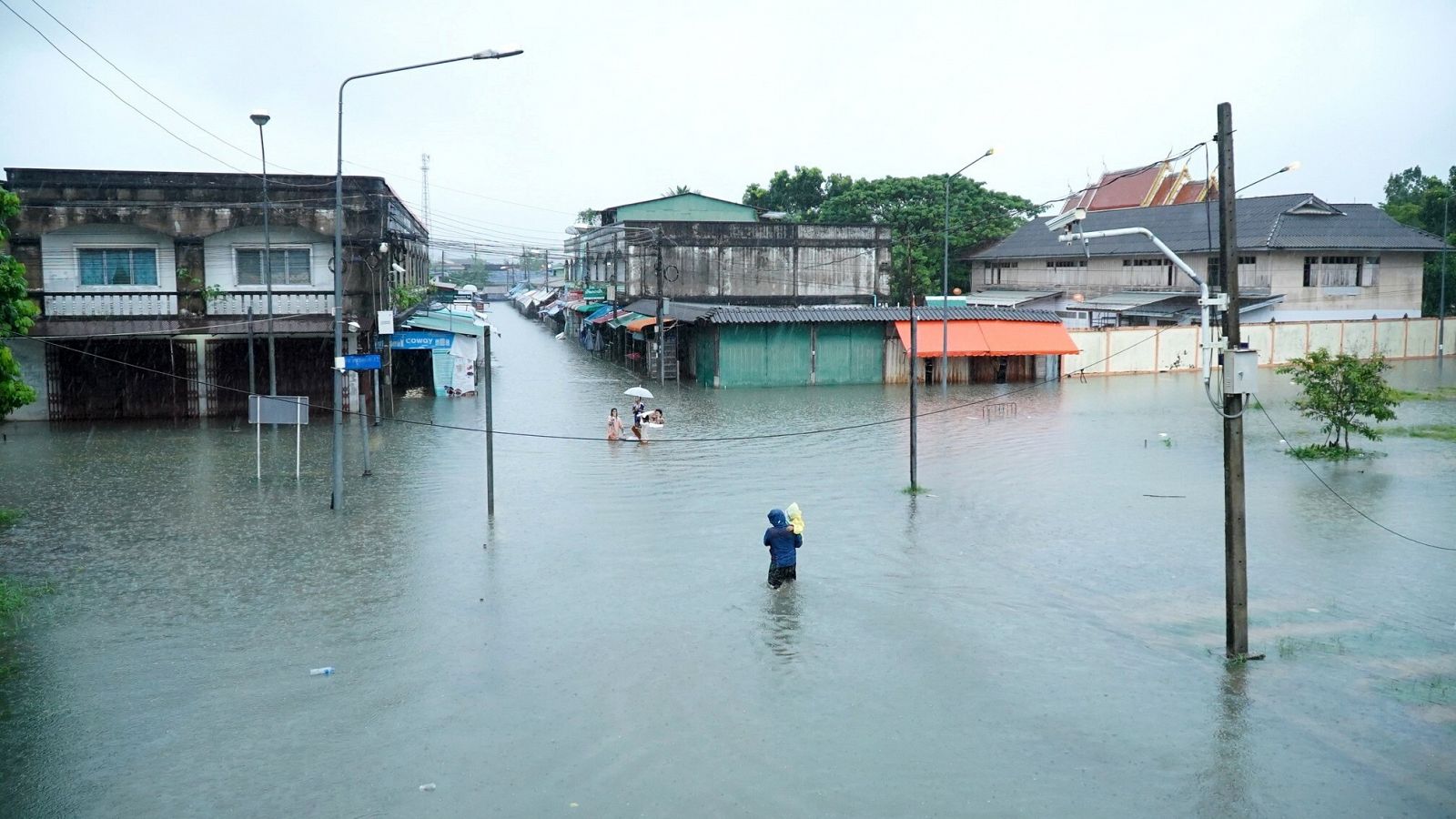 Los habitantes de un pueblo inundado de la provincia de Yala, en el sur de Tailandia, vadeando las aguas