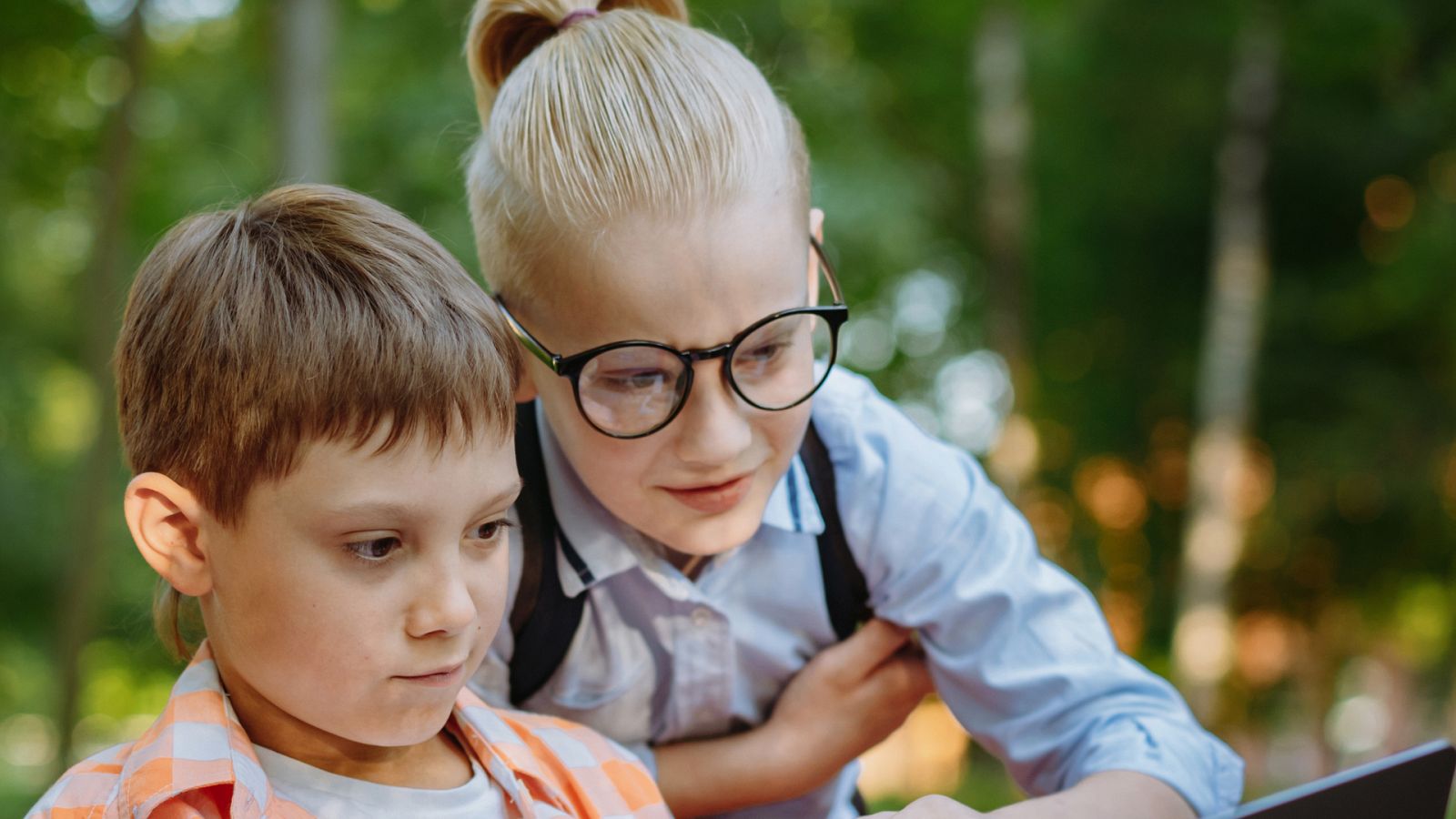 Dos compañeros de clase pendientes de una clase en un dispositivo móvil.