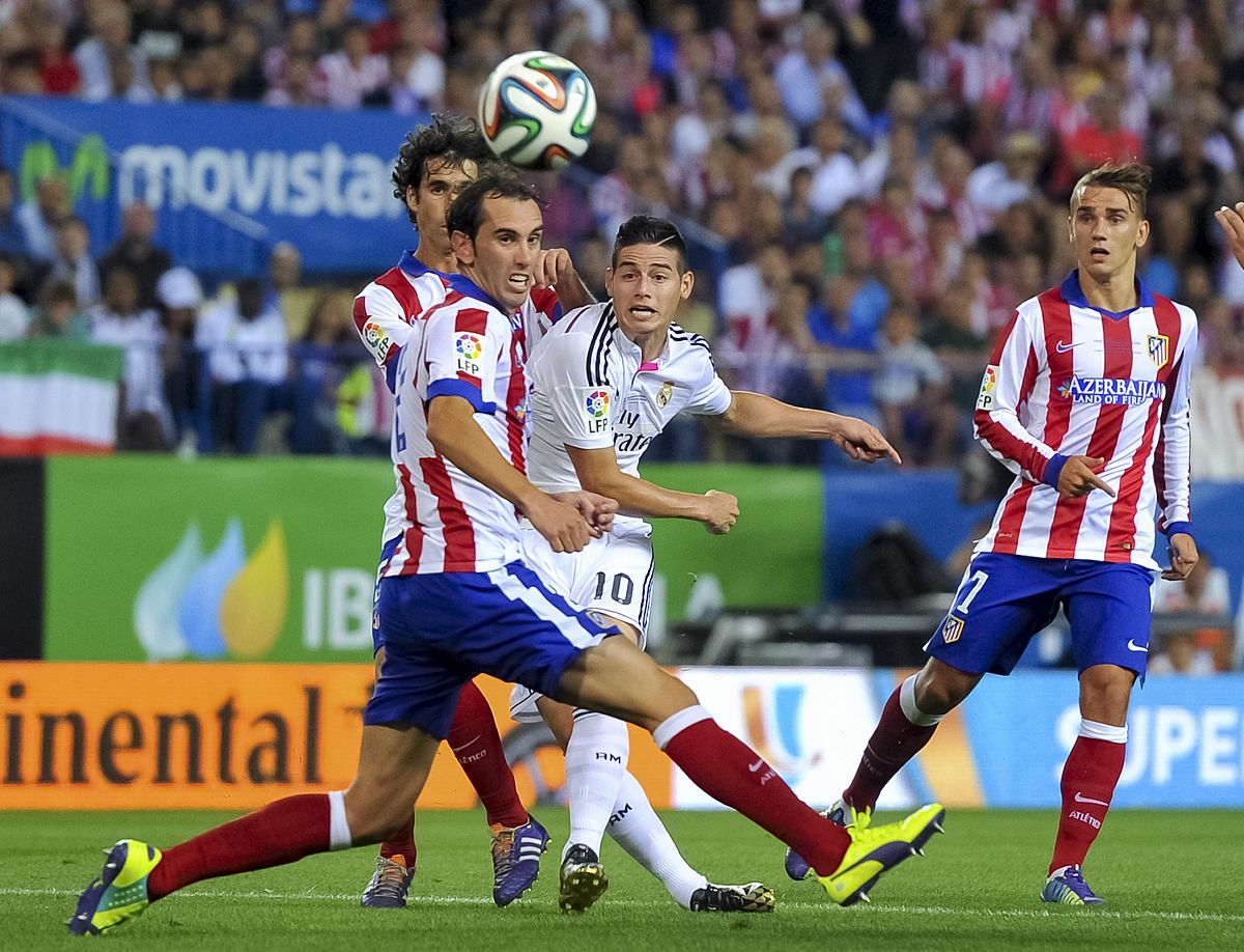 El madridista James Rodriguez (C) intenta llevarse el balón entre Godín, Tiago y Griezmann.