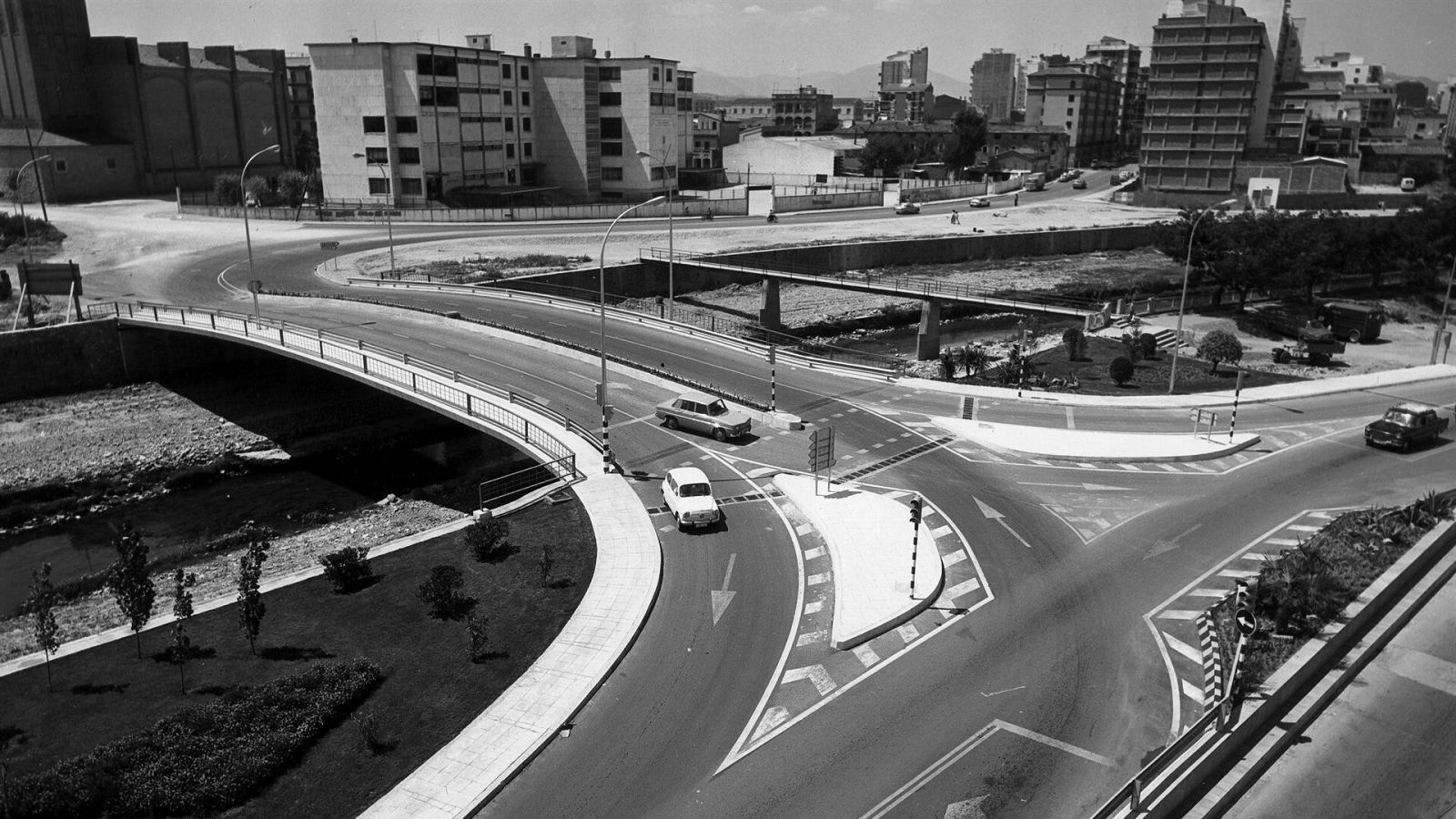 Foto blanco y negro con pocos coches en un gran puente de asfalto sobre un río.