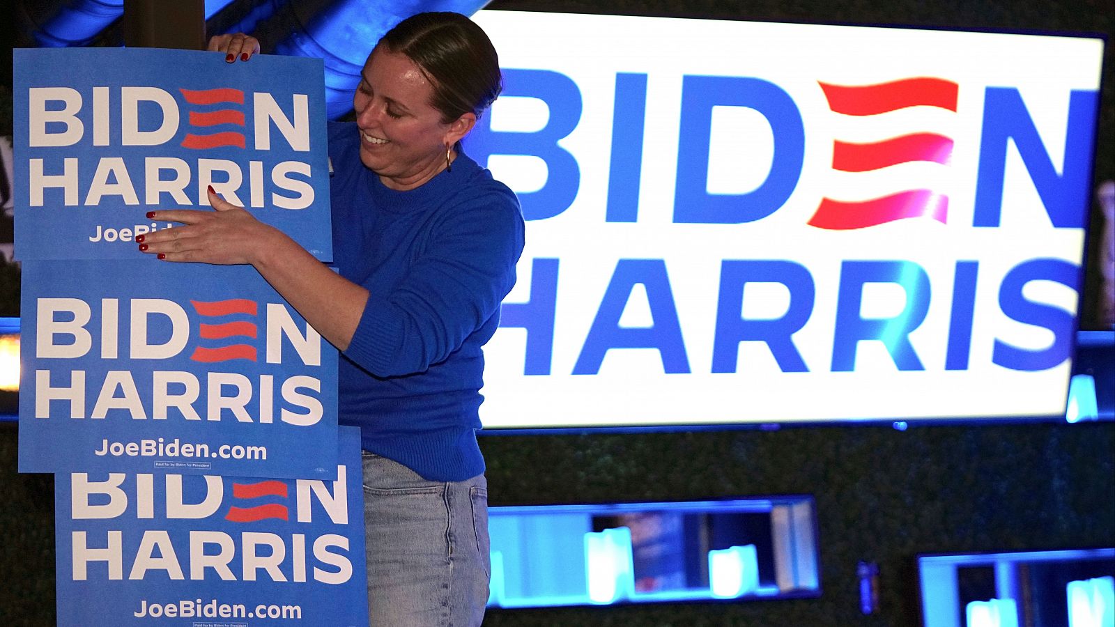 Una miembro del equipo de campaña de Joe Biden coloca unos carteles
