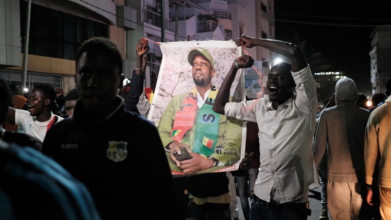 Manifestantes sostienen una foto del líder de la oposición senegalesa mientras celebran su excarcelación y la del candidato presidencial