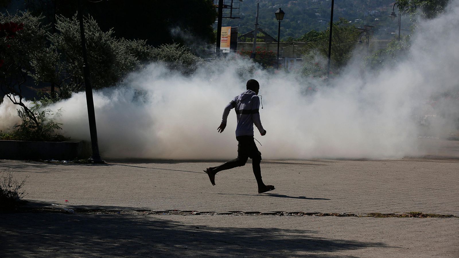 Un hombre corre mientras la Policía Nacional de Haití lanza gases lacrimógenos