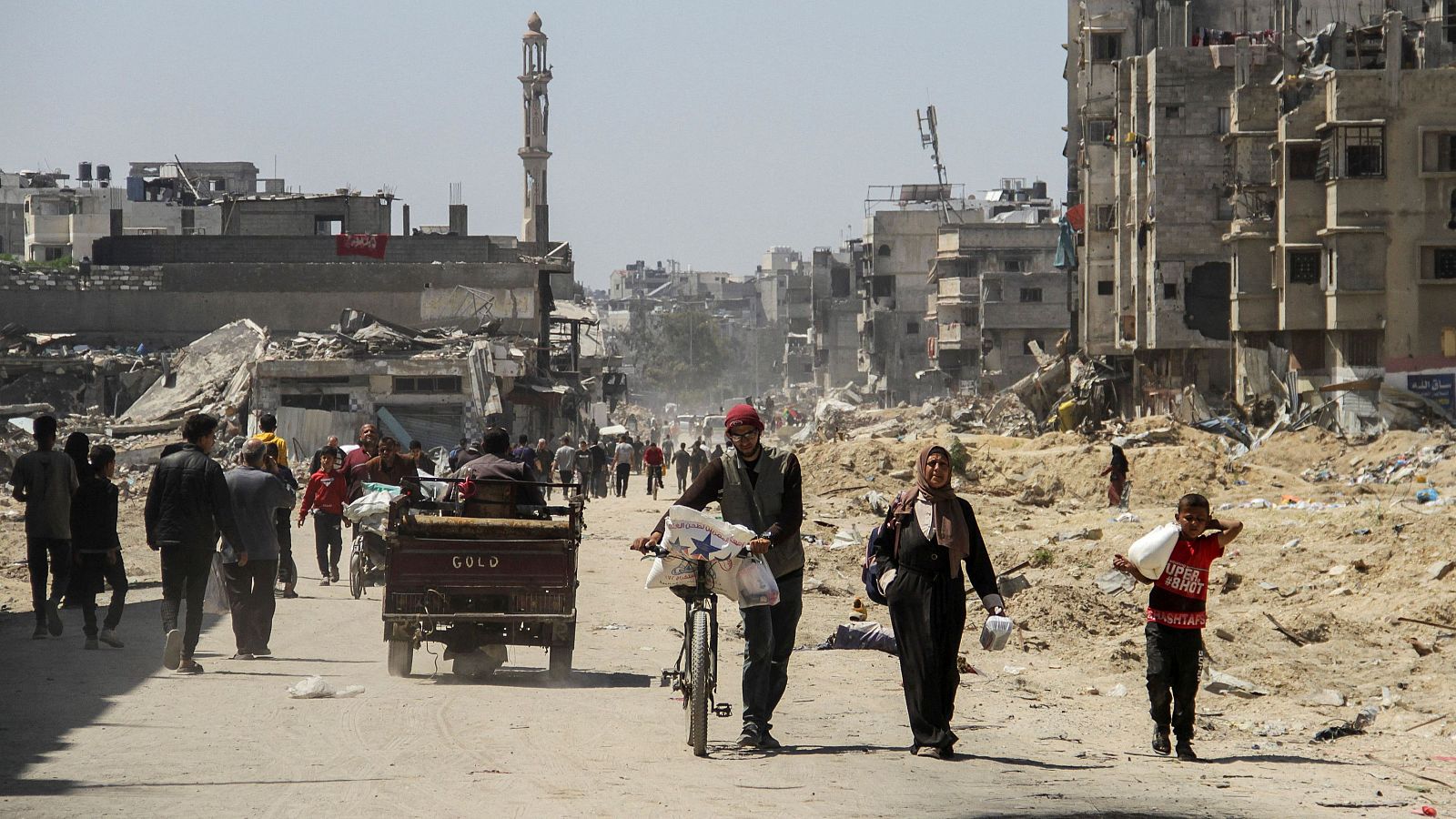 Palestinos transportan ayuda mientras otros luchan por recibir su parte en medio de un hambre generalizada en Gaza.