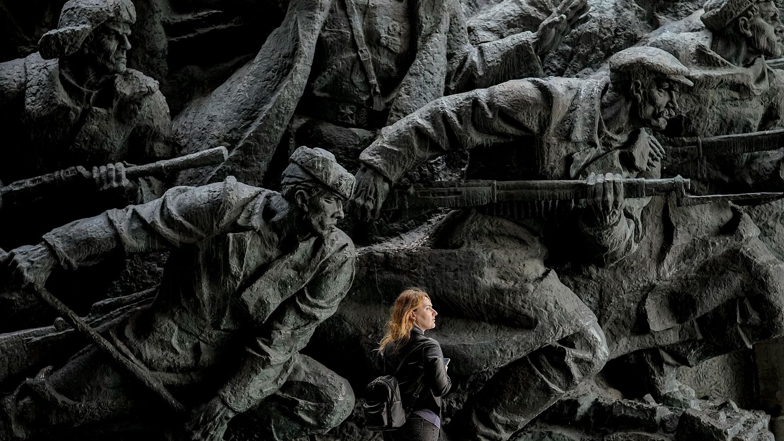 Una mujer camina bajo esculturas que representan escenas de la Segunda Guerra Mundial en el Museo Nacional de Historia de Ucrania en Kiev