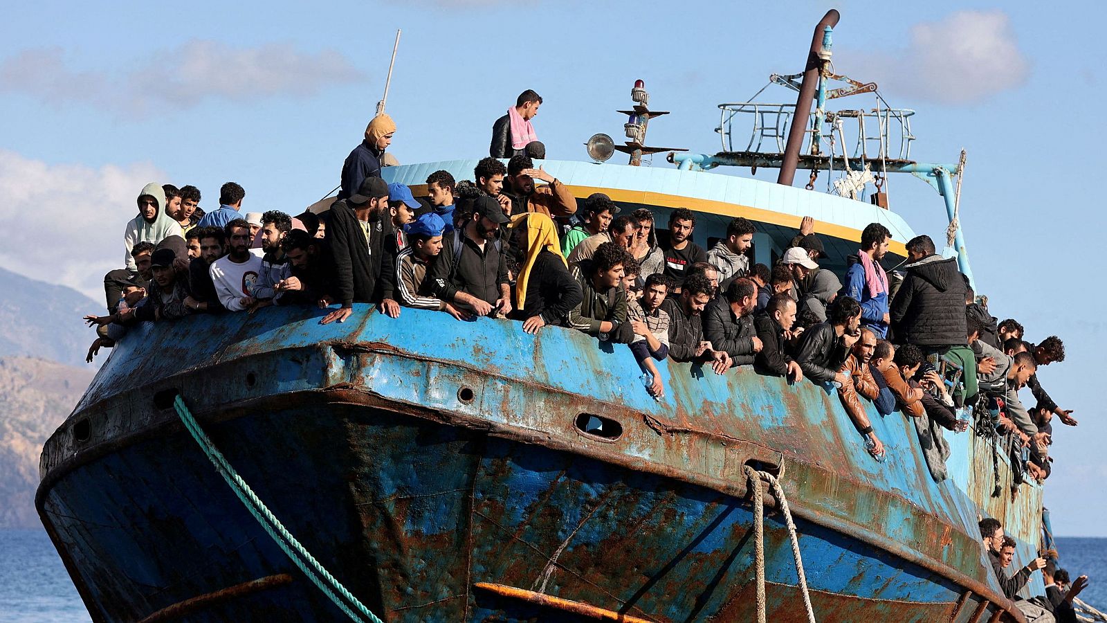 Migrantes sentados a bordo de un barco pesquero en el puerto de Paleochora