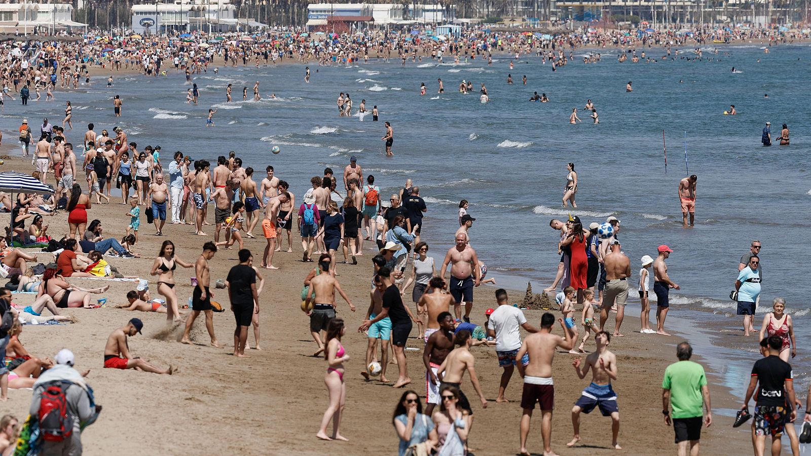 Decenas de personas pasean en bañador por la playa de la Malvarrosa, en Valencia, para sofocar el episodio de calor de mediados de abril.
