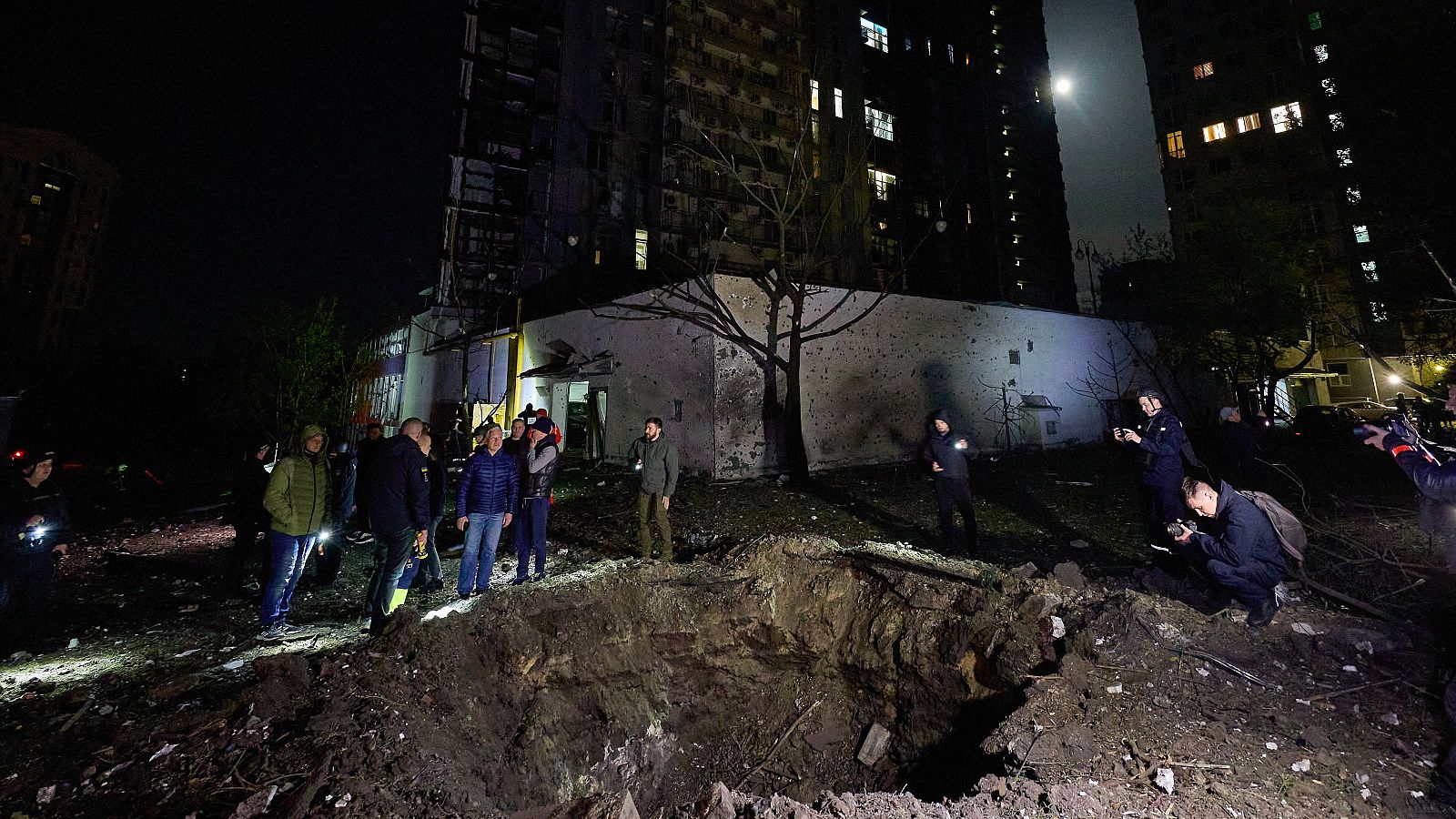 Un grupo de civiles se asoma a un cráter que ha dejado un ataque ruso sobre la ciudad de Kharkiv