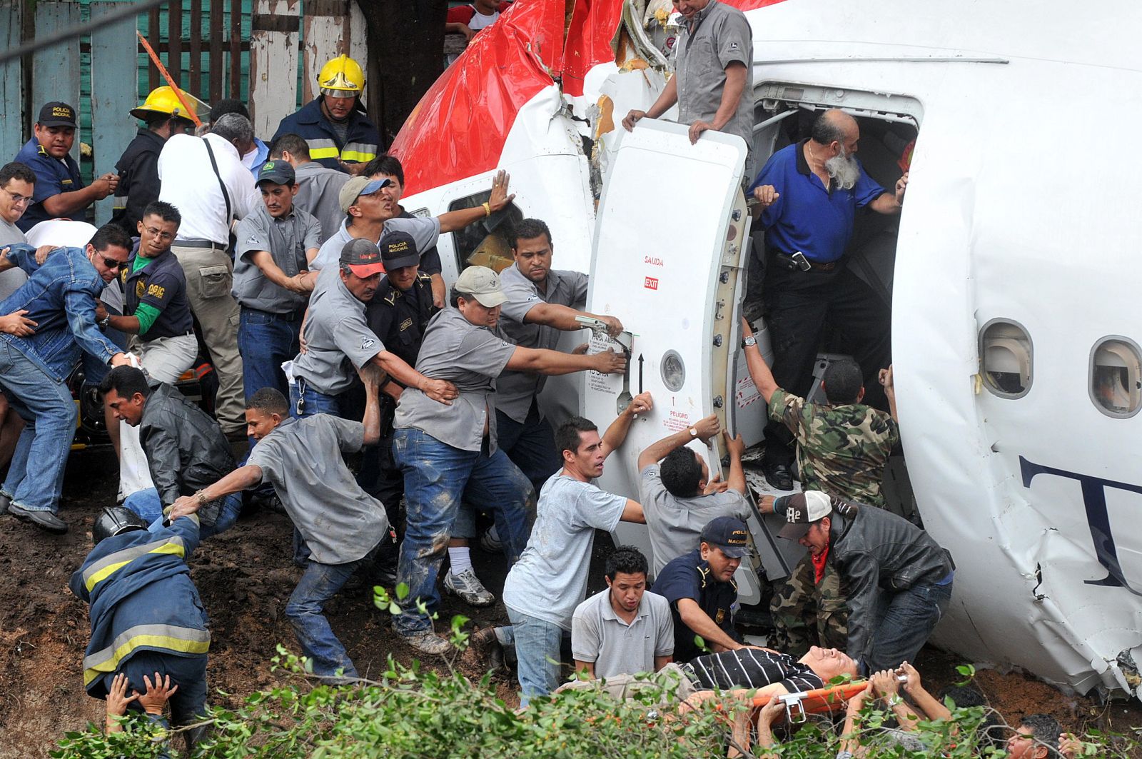 Hondureños ayudan en las labores de rescate y evacuación de los pasajeros del avión de la aerolínea TACA procedente de El Salvador que se salió de la pista tras aterrizar en el aeropuerto de Tegucigalpa, causando una cantidad no precisada de heridos