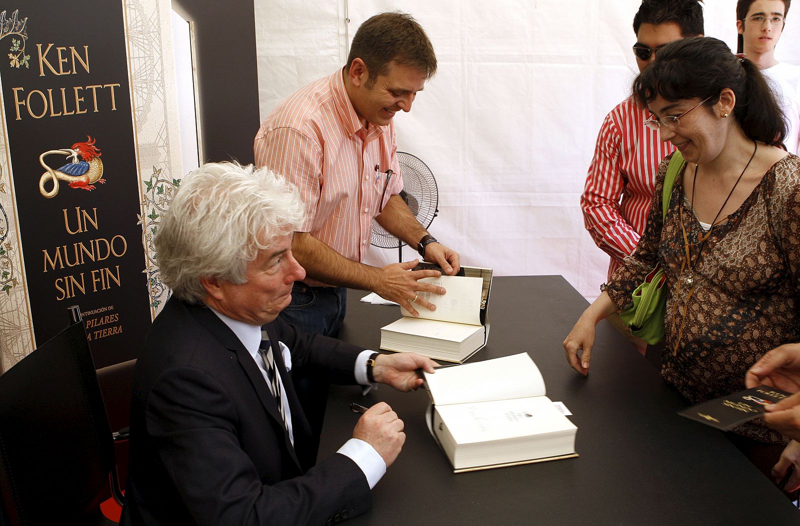 El escritor galés Ken Follet firma un ejemplar de su última novela, "Un mundo sin fin", a una lectora durante la firma de libros que ha realizado en la Feria del Libro de Madrid.