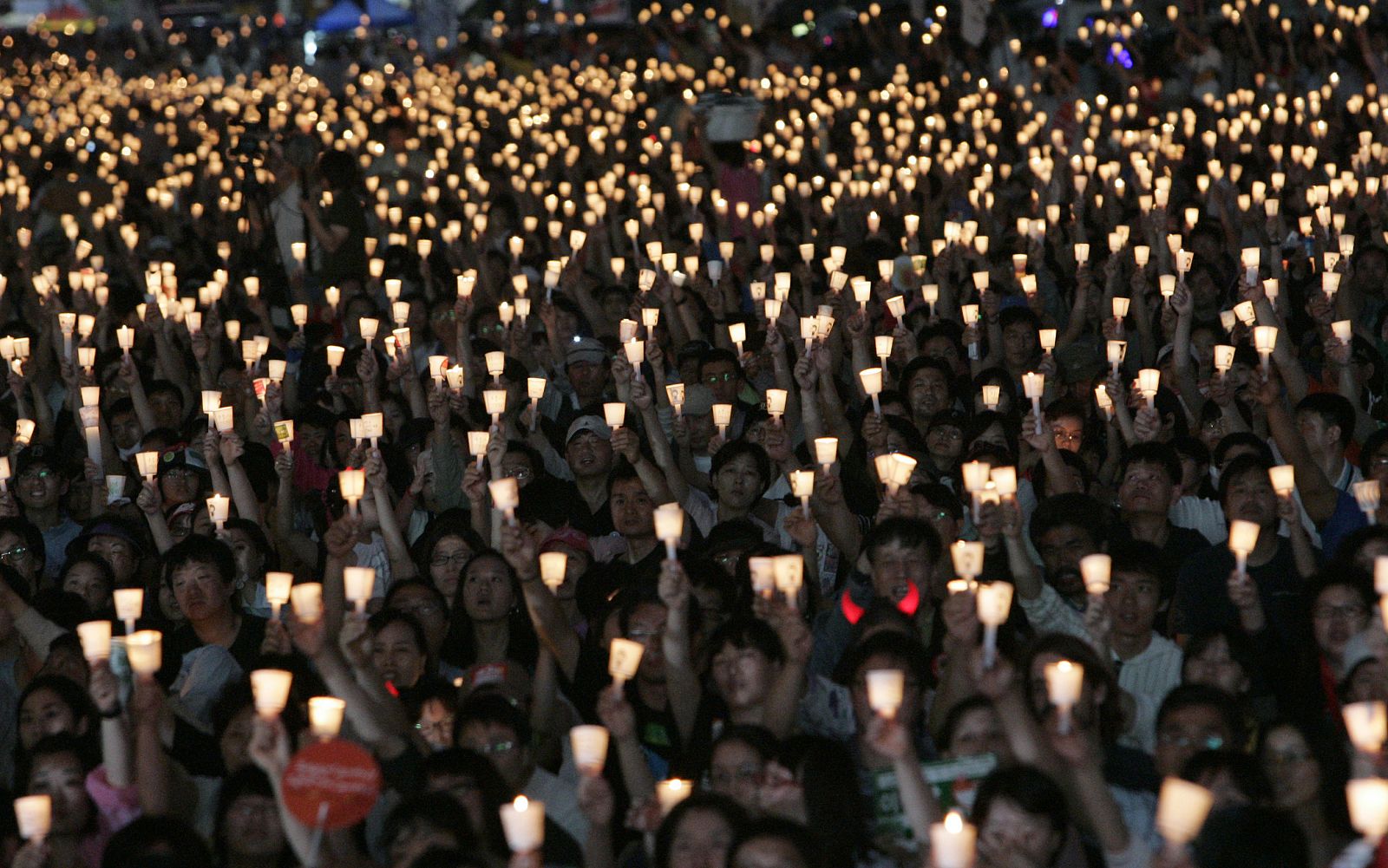 Protesters raise candles during a candle-light rally demanding a full-scale renegotiation of the beef deal with the U.S. in Seoul