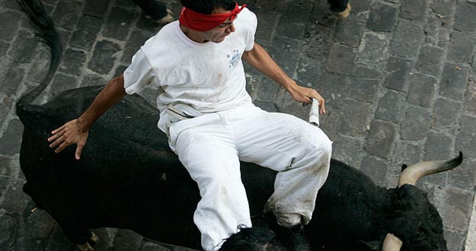 Un mozo a lomos de un toro en uno de los encierros de San Fermín.