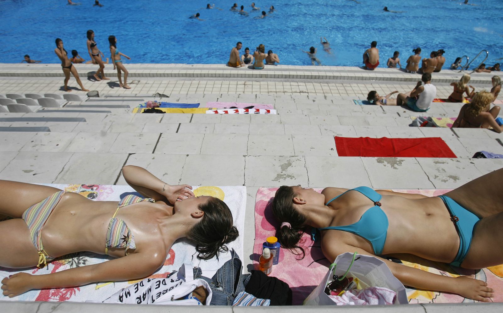 Unas jóvenes toman el sol tranquilamente en una piscina.