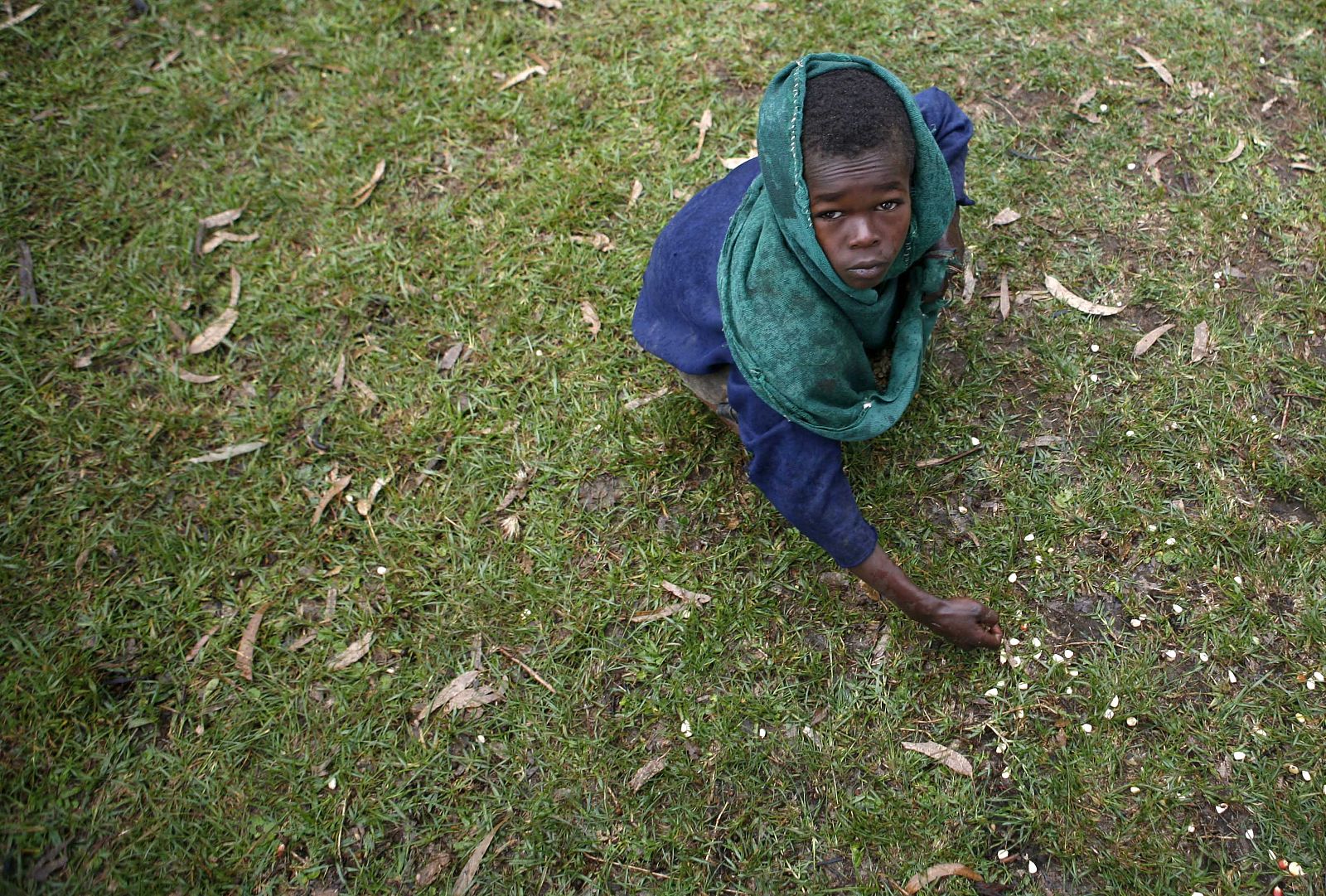 Un niño recoge maíz del suelo durante una distribución de alimentos organizada por Cruz Roja Internacional en Volayta (Etiopía).