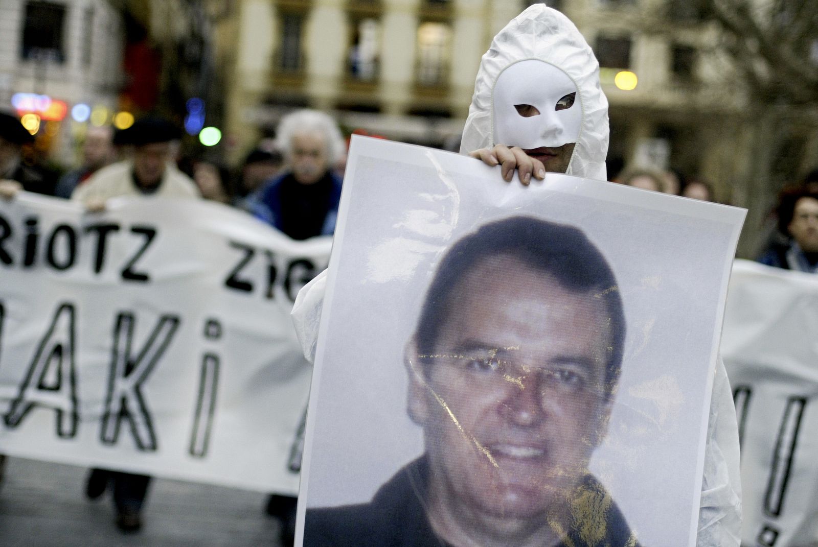 A masked protester carries a picture of Inaki de Juana Chaos during a demonstration in San Sebastian