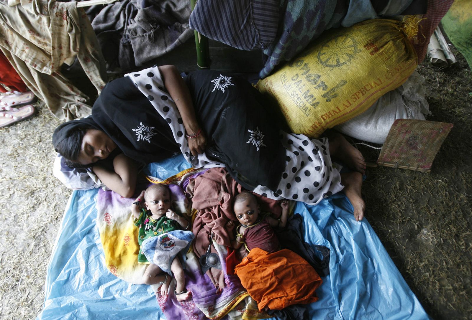 Una mujer duerme junto con sus hijos tras ser evacuada debido a las inundaciones que asolan India