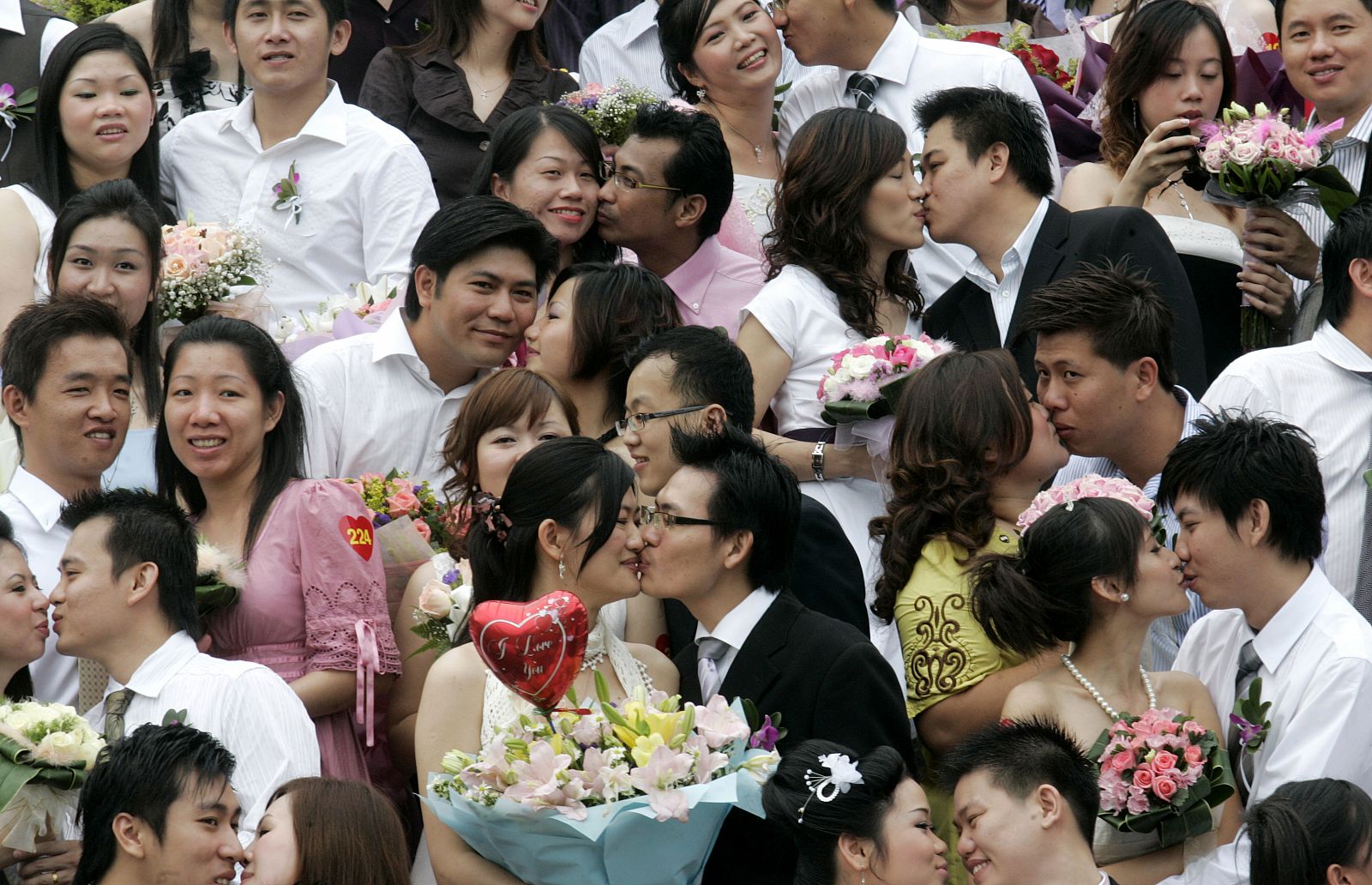 Ethnic Chinese Malaysians pose as they kiss for a group photo during their mass wedding ceremony, in conjunction with the date 08.08.08, in Klang