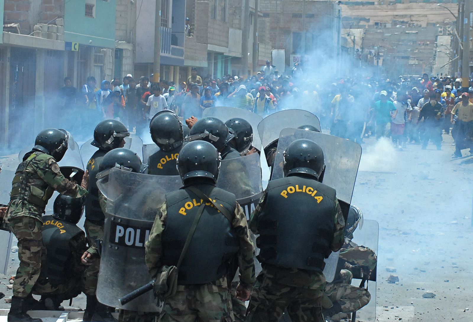 Un grupo de policias anti disturbios se enfrentan contra manifestantes en Tacna (Perú) que protestan contra la modificación de la ley del canon minero.