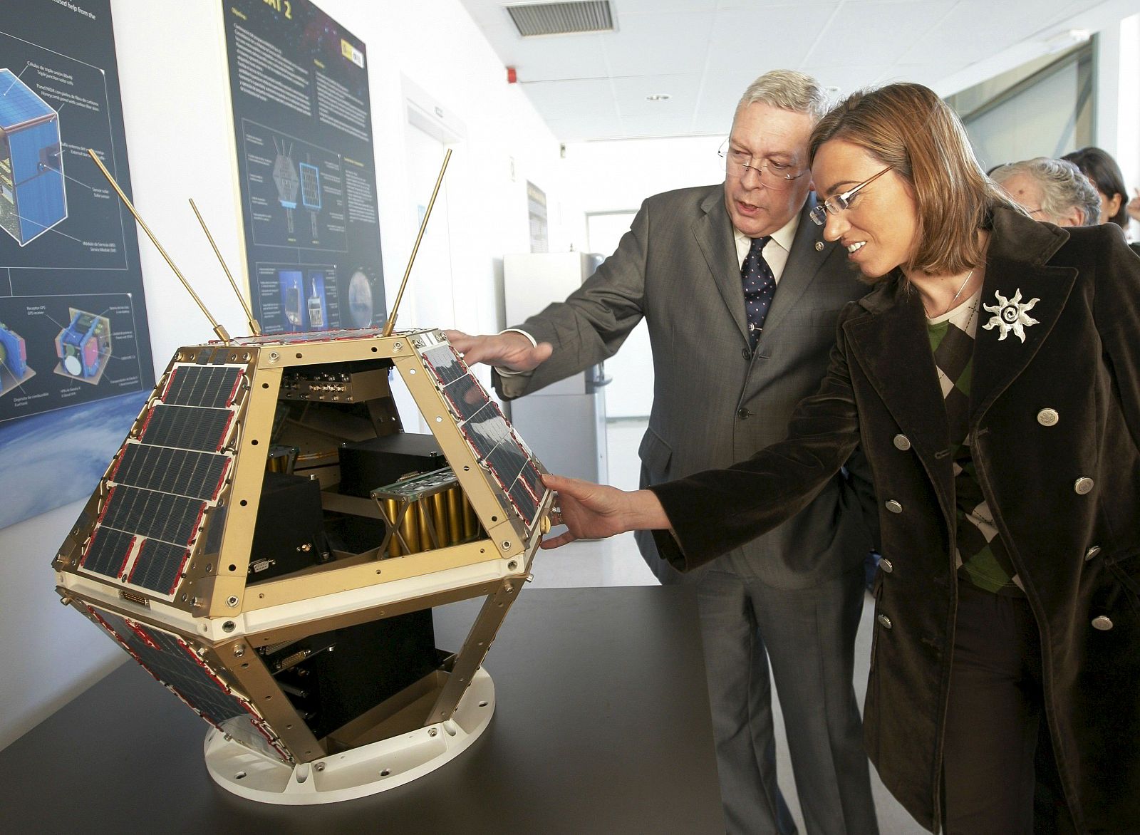 La ministra de Defensa, Carme Chacón, acompañada del director general del INTA, Fernando González, observa una maqueta antes de la firma del contrato para la fabricación del satélite "Paz" (06/11/08).