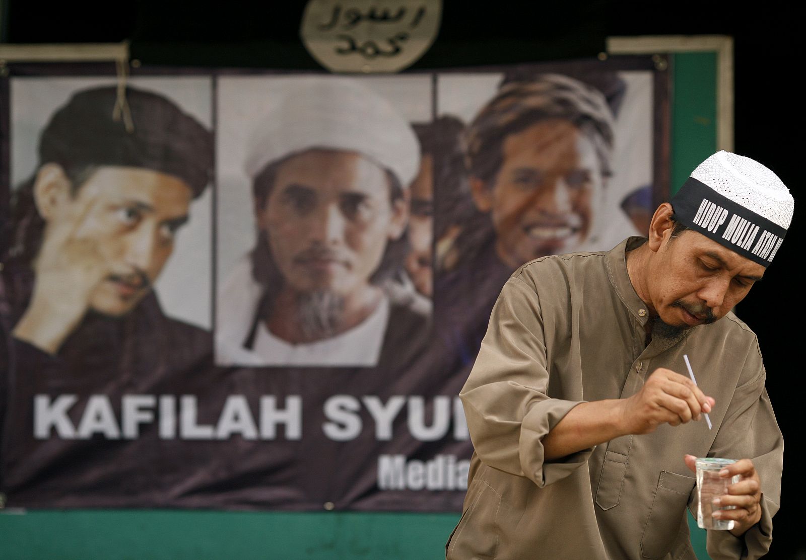 Un indonesio bebe delante de un poster de los condenados en Tenggulum, en la provincia de Java.