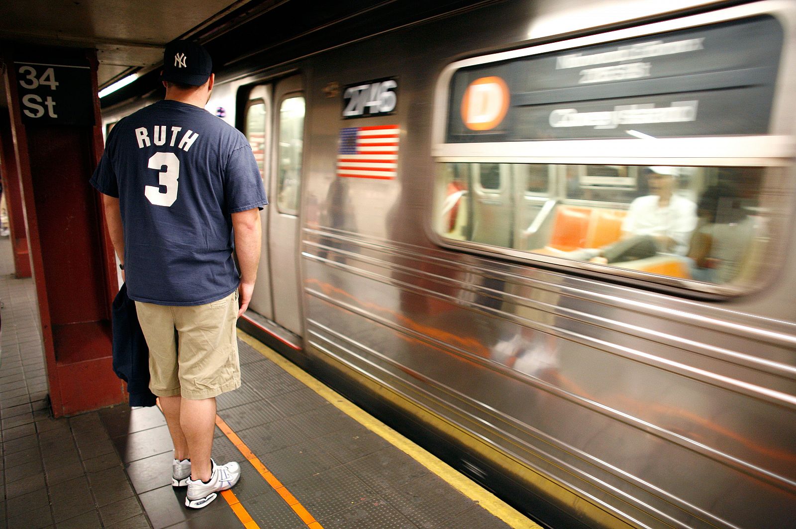Un hombre espera el metro de Nueva York con una camiseta de los Yankees.