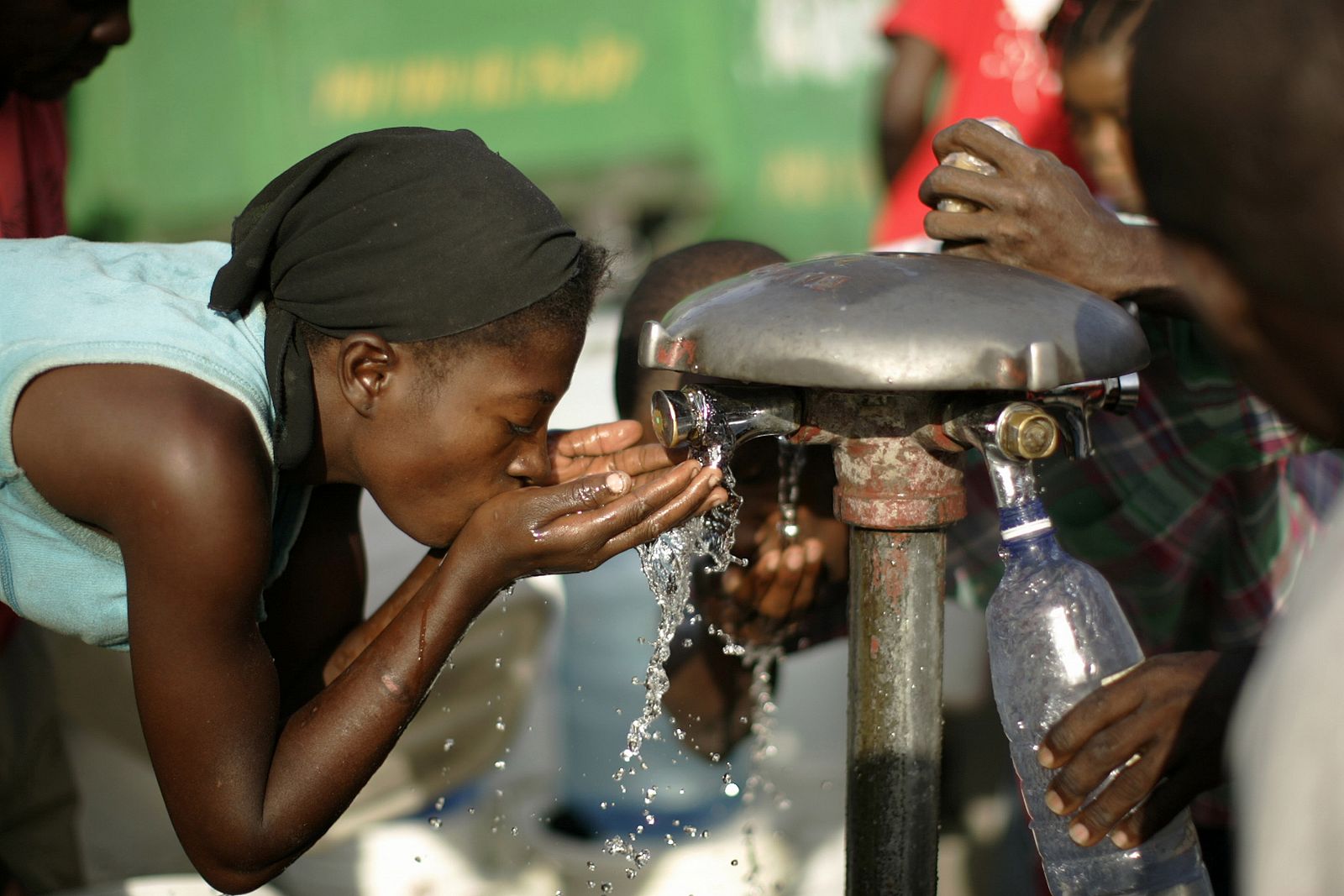 A Haitian woman drinks water from a communal water pipe in Port-au-Prince