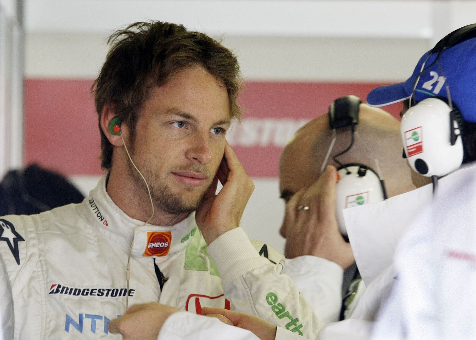 Honda F1 driver Jenson Button of England listens to his mechanic during a testing session at the Catalonia racetrack in Montmelo