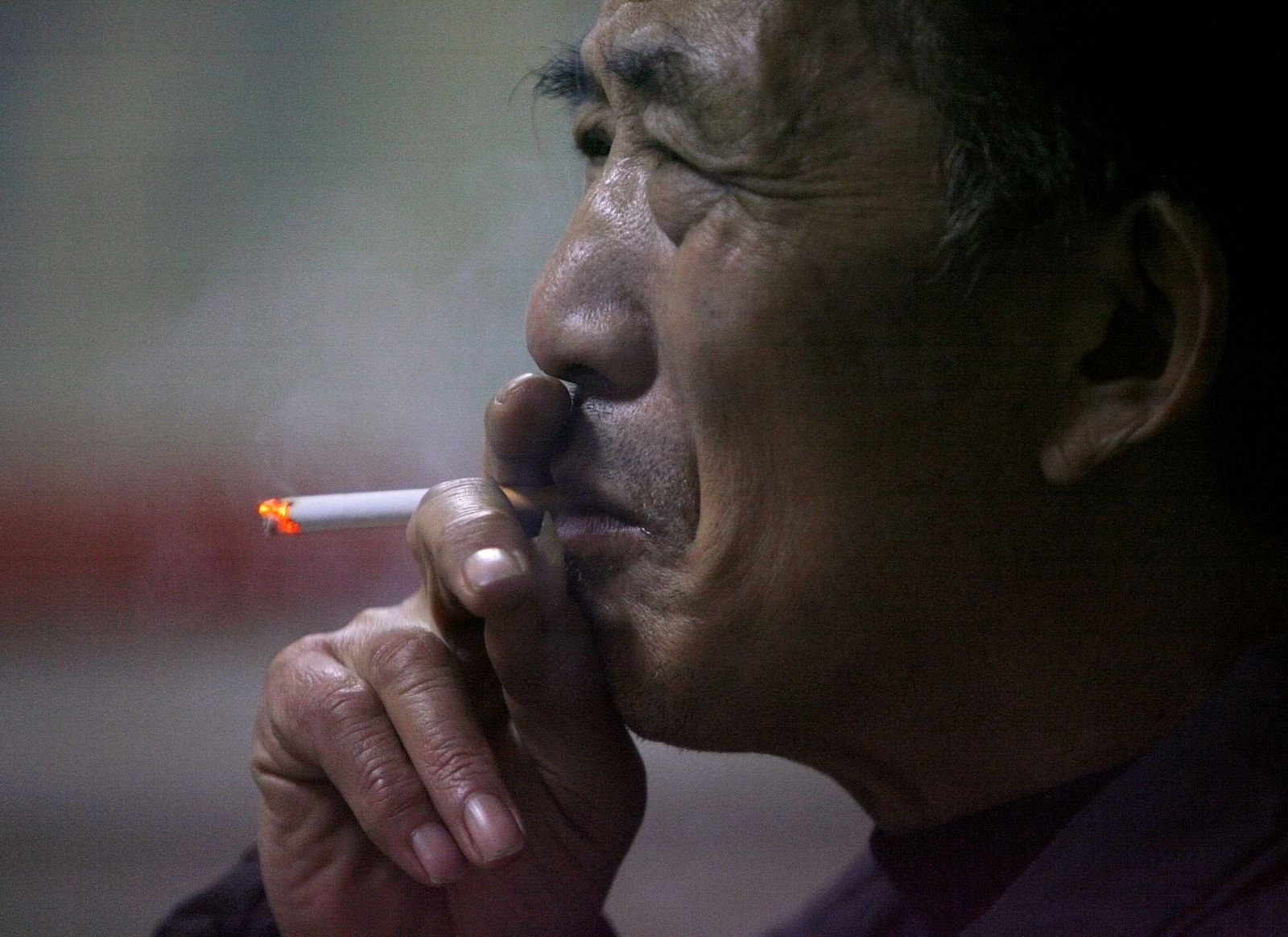 Un anciano fuma un cigarrillo en un mercado de Nanjing.